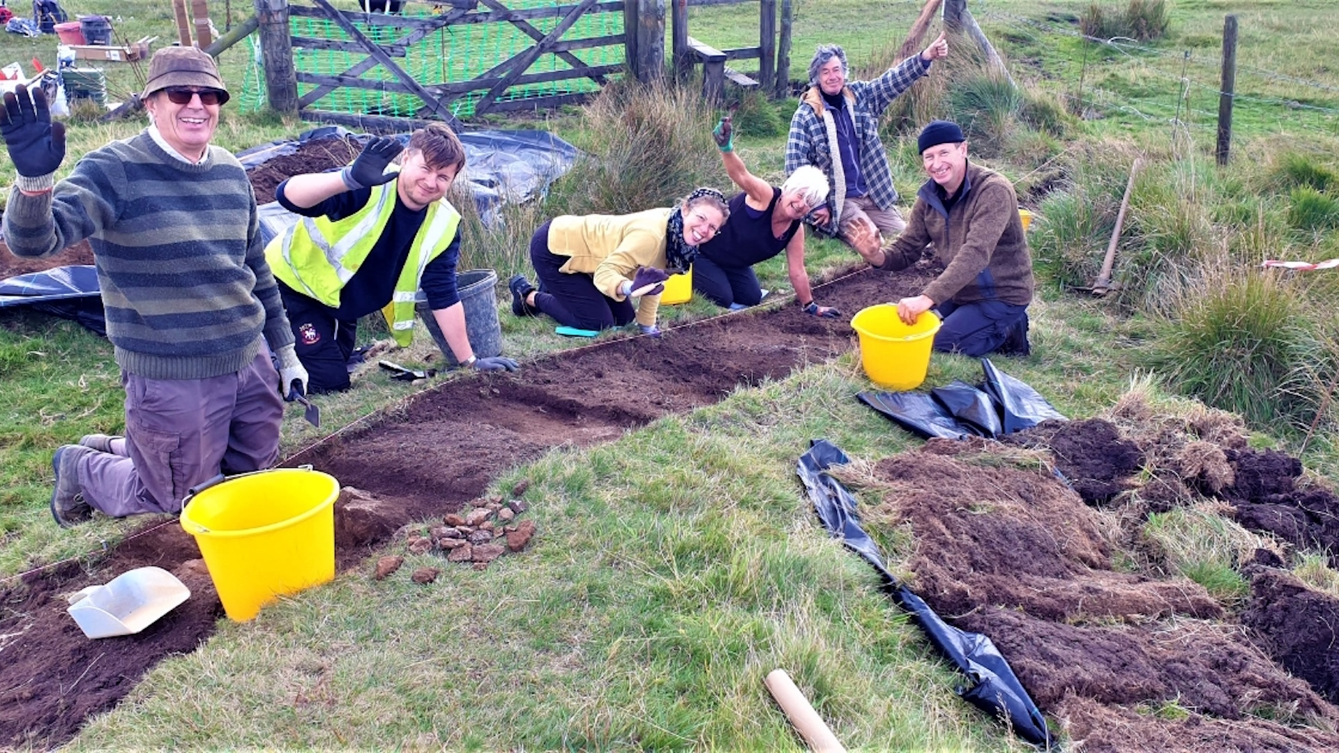 A group of people excavates a site in a grassy field