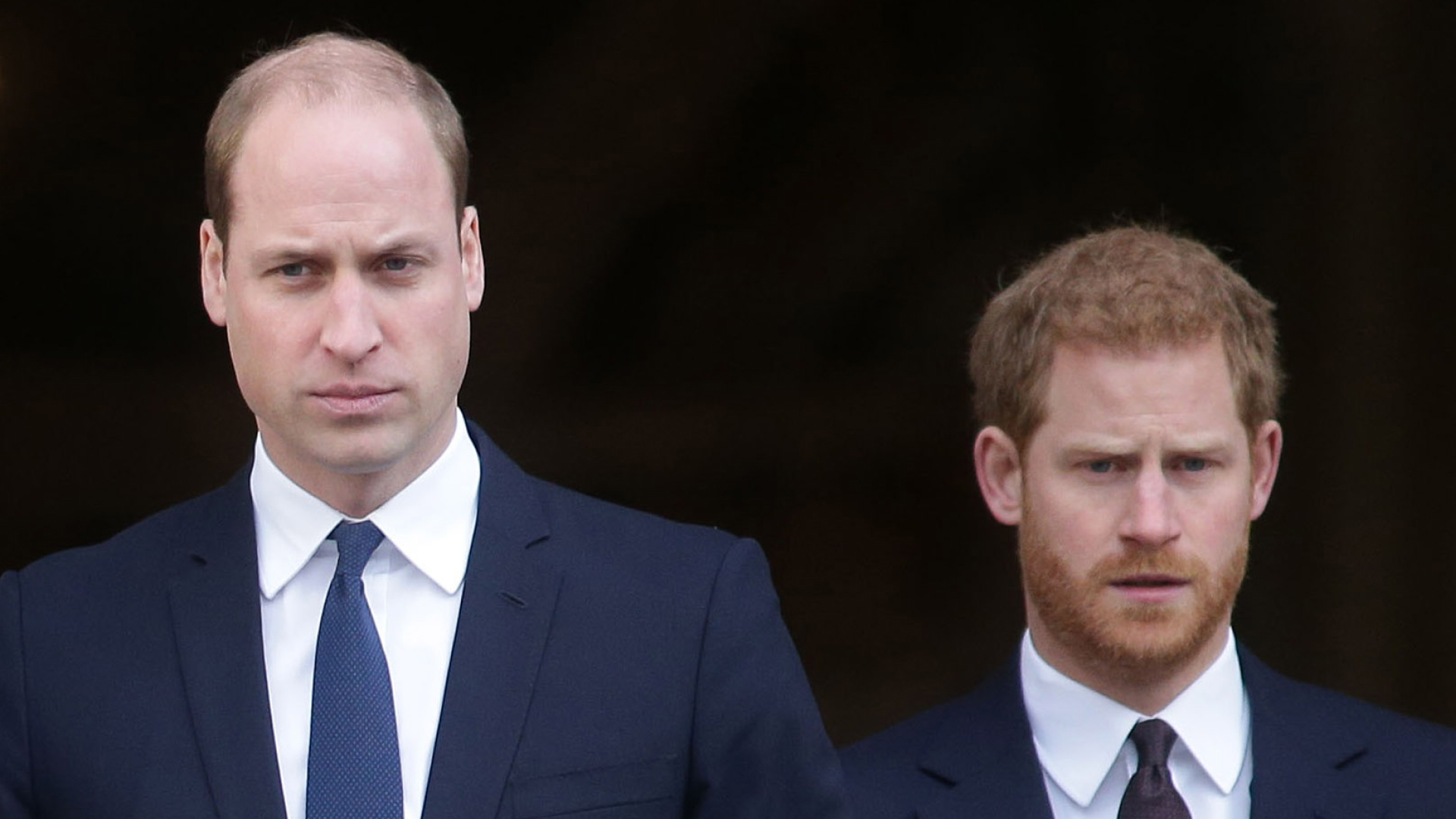 Prince William and Prince Harry both wear white shirts with navy suits