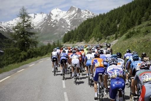 The snow-capped Alps loom ahead of the peloton.