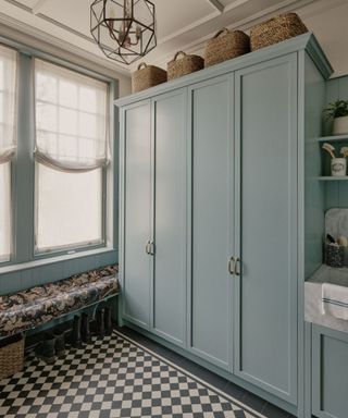 small white boot room with blue painted storage cabinetry and traditional victorian checkerboard flooring