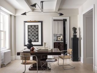 dining room with white walls, a chunky, glossy wood dining table, metal dining chairs, a large black piece of artwork and a statue