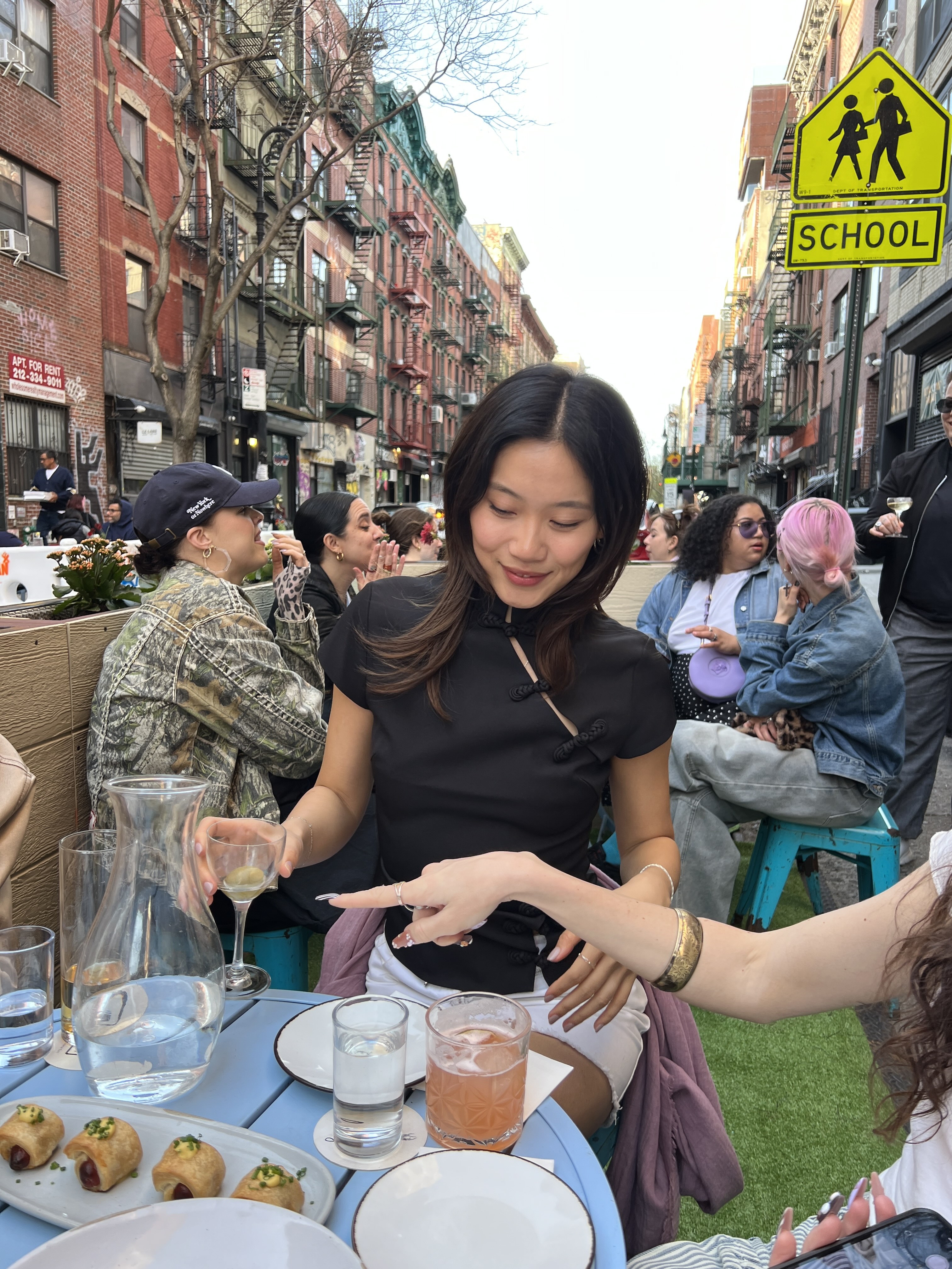 Vivian Li eating lunch in NYC wearing a traditional black Tang jacket and a white skirt