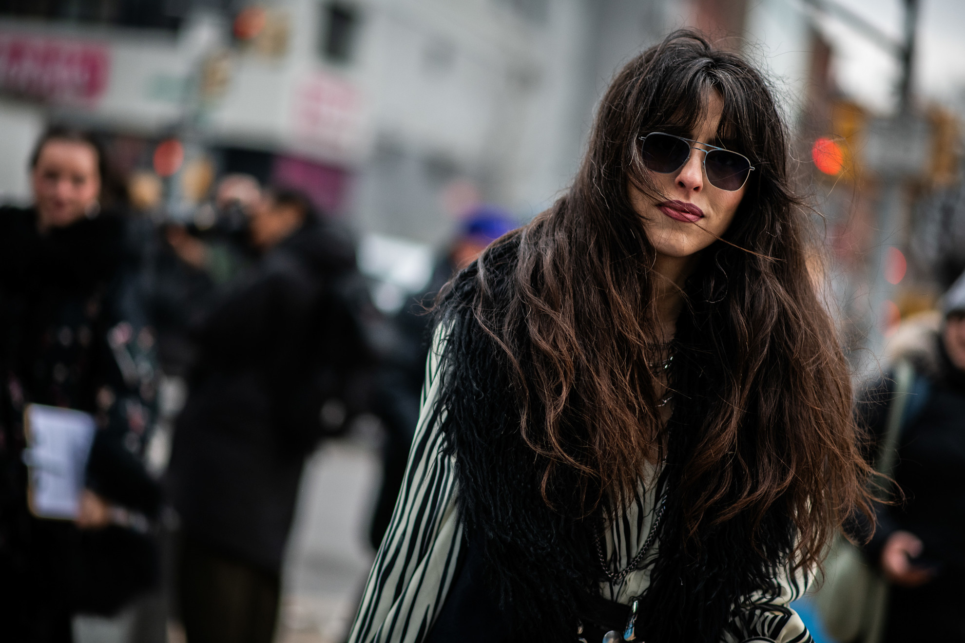 a woman with long dark brunette hair in black and white jacket and sunglasses