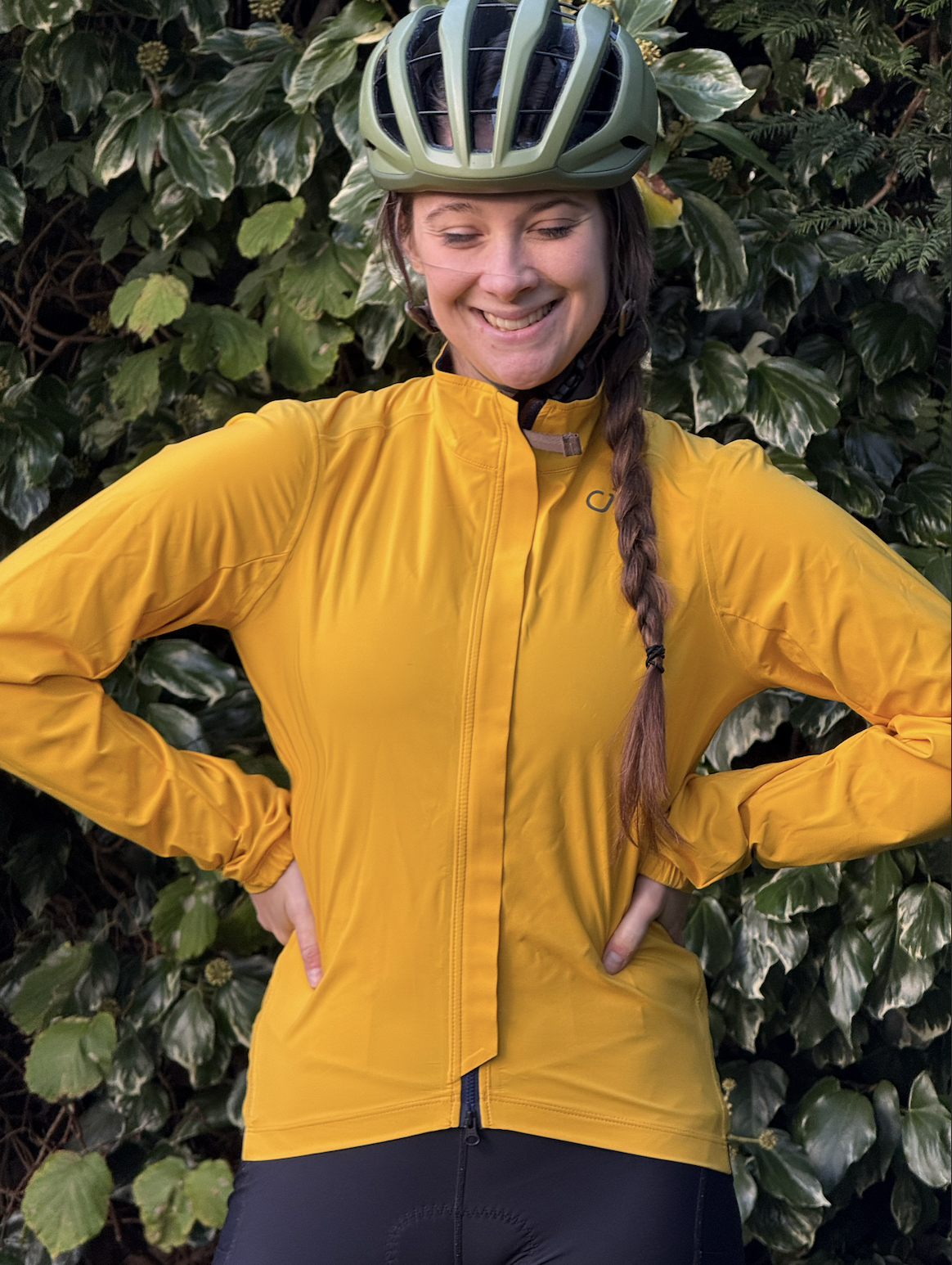 Woman stands facing forward in yellow velocio jacket hands on hips