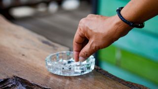 Man stubbing out cigarette in ash tray