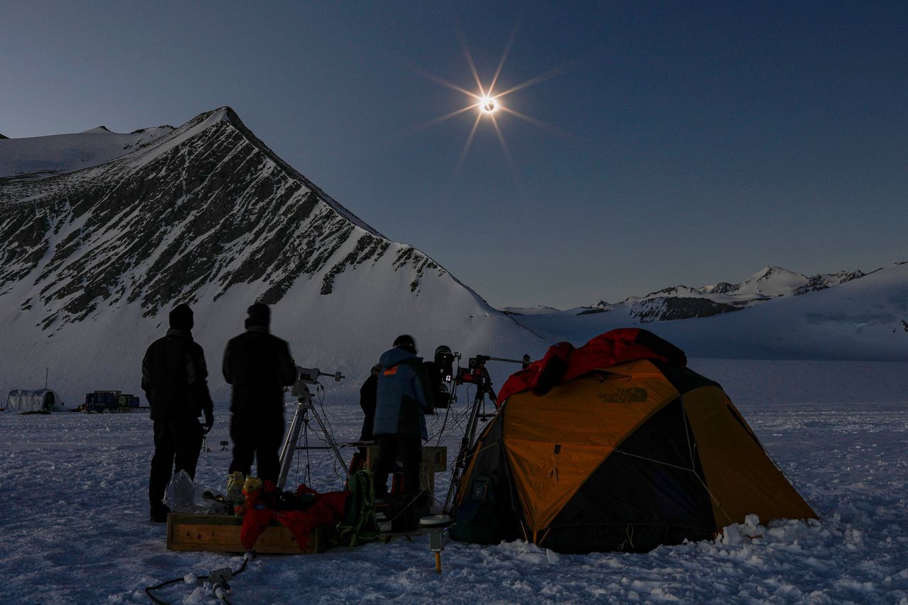This handout picture released by Imagen Chile shows Chilean and US scientists looking at a solar eclipse from the Union Glacier in Antarctica on December 4, 2021.
