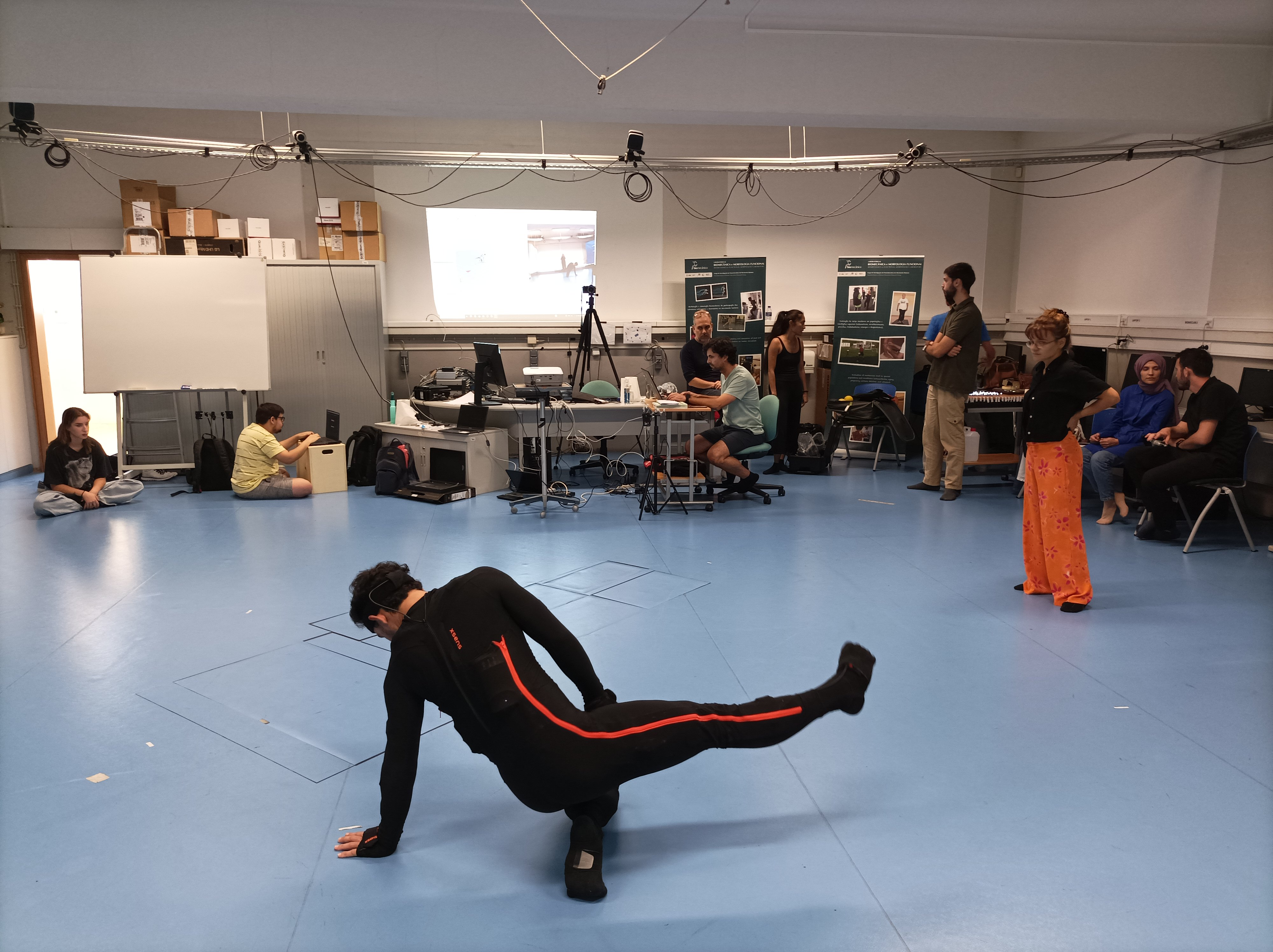 People dancing wearing black in front of a screen
