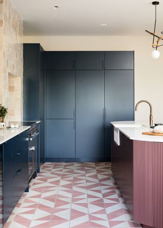 A navy blue kitchen cabinet and tall cabinets and a deep purple kitchen island with a white countertop