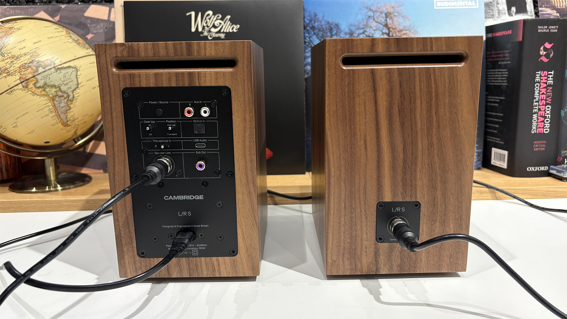 Cambridge Audio L/R S desktop speakers on white surface in front of bookcase,rear of cabinets showing connections
