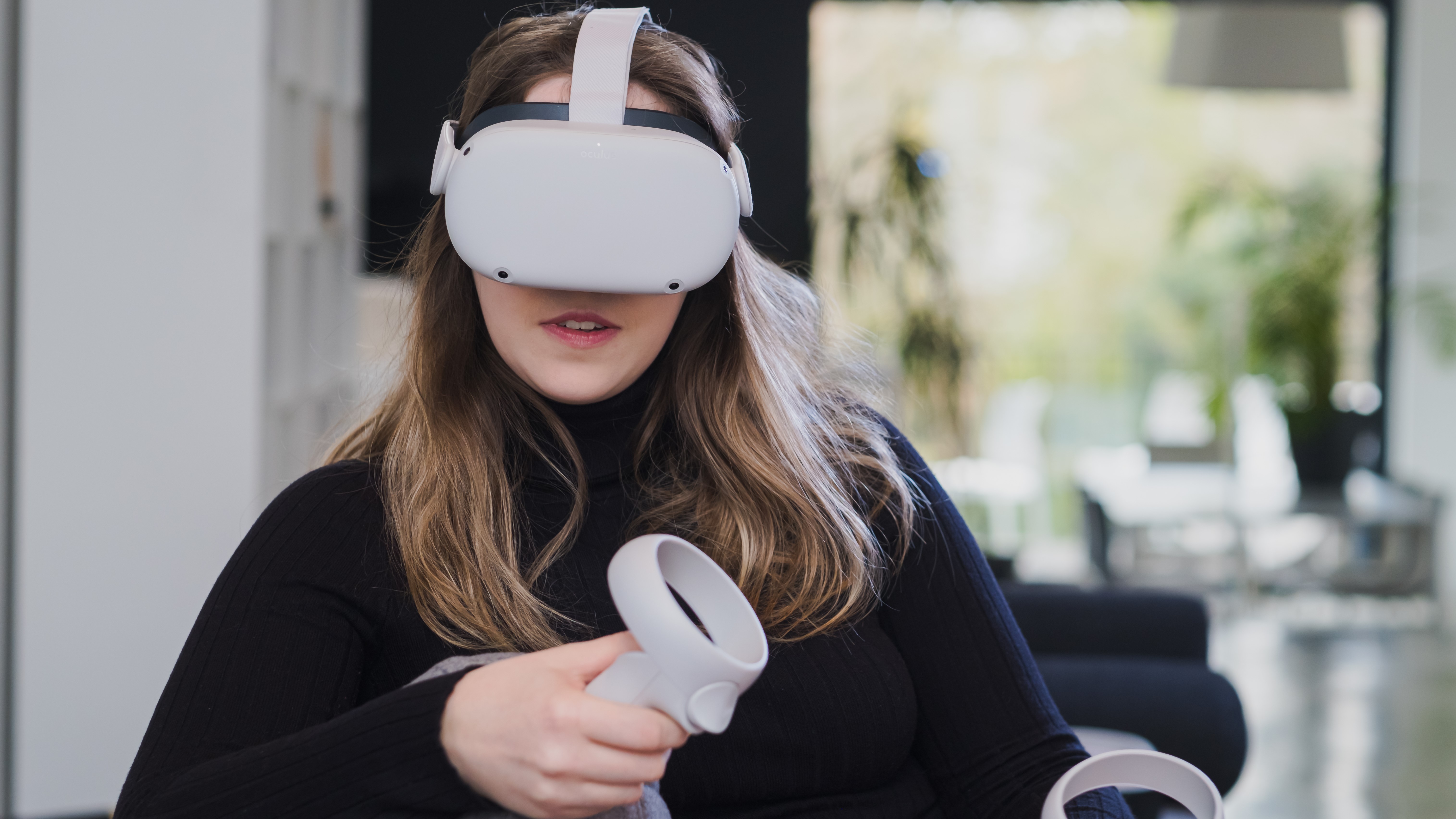 A person sat on a couch while wearing an Oculus Quest 2 headset