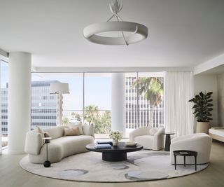 A white living room with high ceilings and floor to ceiling windows