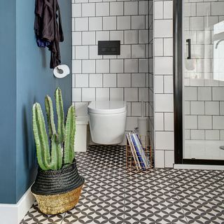 monochrome bathroom with blue wall, black and white tiles and a cactus in a woven basket