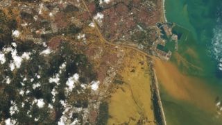 a satellite photo showing a sea of muddy water covering a large city by the coast