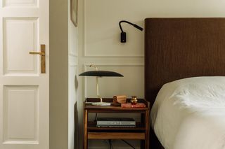 A bedside table with lamp and wall light