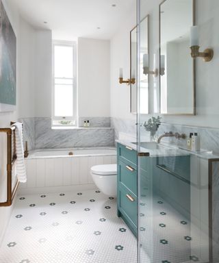white bathroom with aqua vanity, tongue and groove bath panel and patterned floor