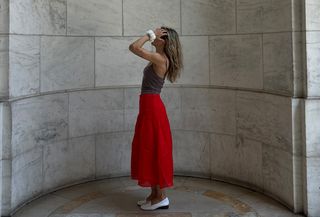 Eliza Huber wearing a red midi skirt, tan camisole, white loafers, and white scrunchie from the J.Crew x Maryam Nassir Zadeh collaboration.