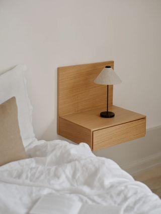 wall-mounted oak bedside table with small wireless lamp