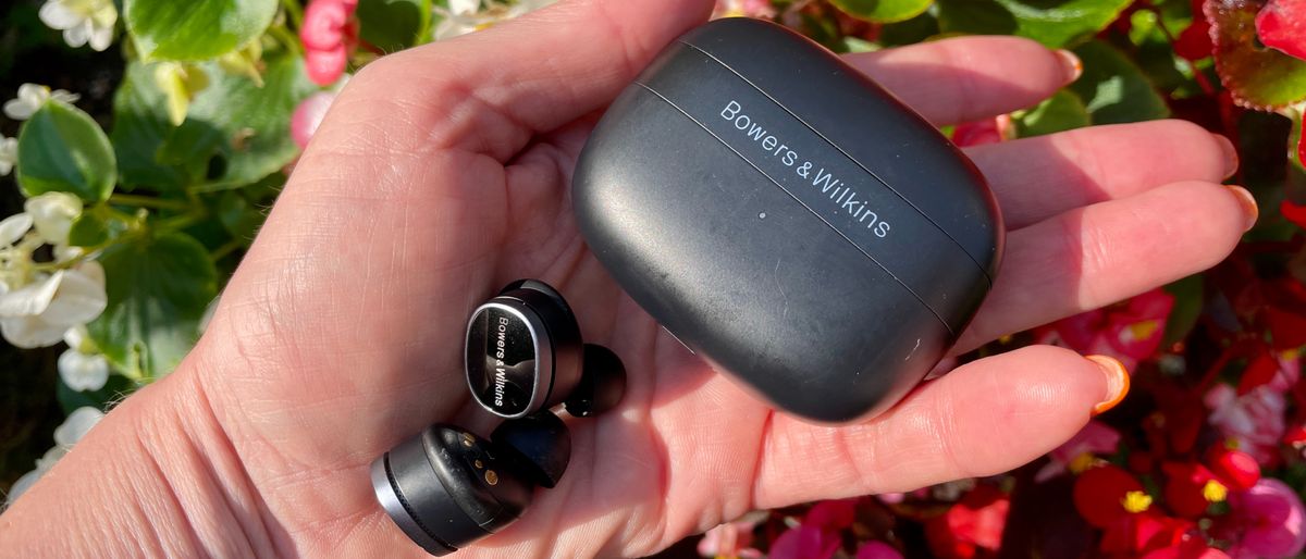 Bowers &amp; Wilkins Pi8 earbuds, held in a hand on grassy background