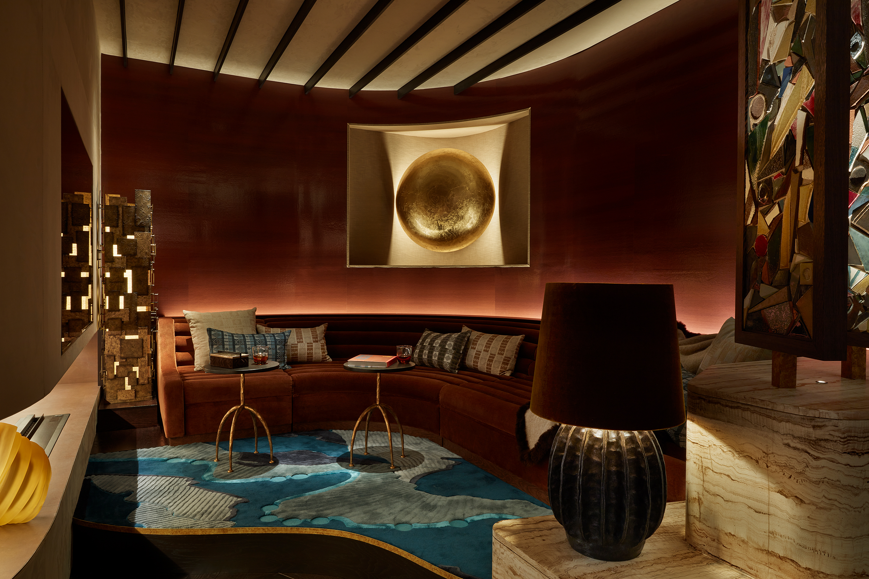 a media room with ambient lighting, terracotta walls and a large curved l shape sofa