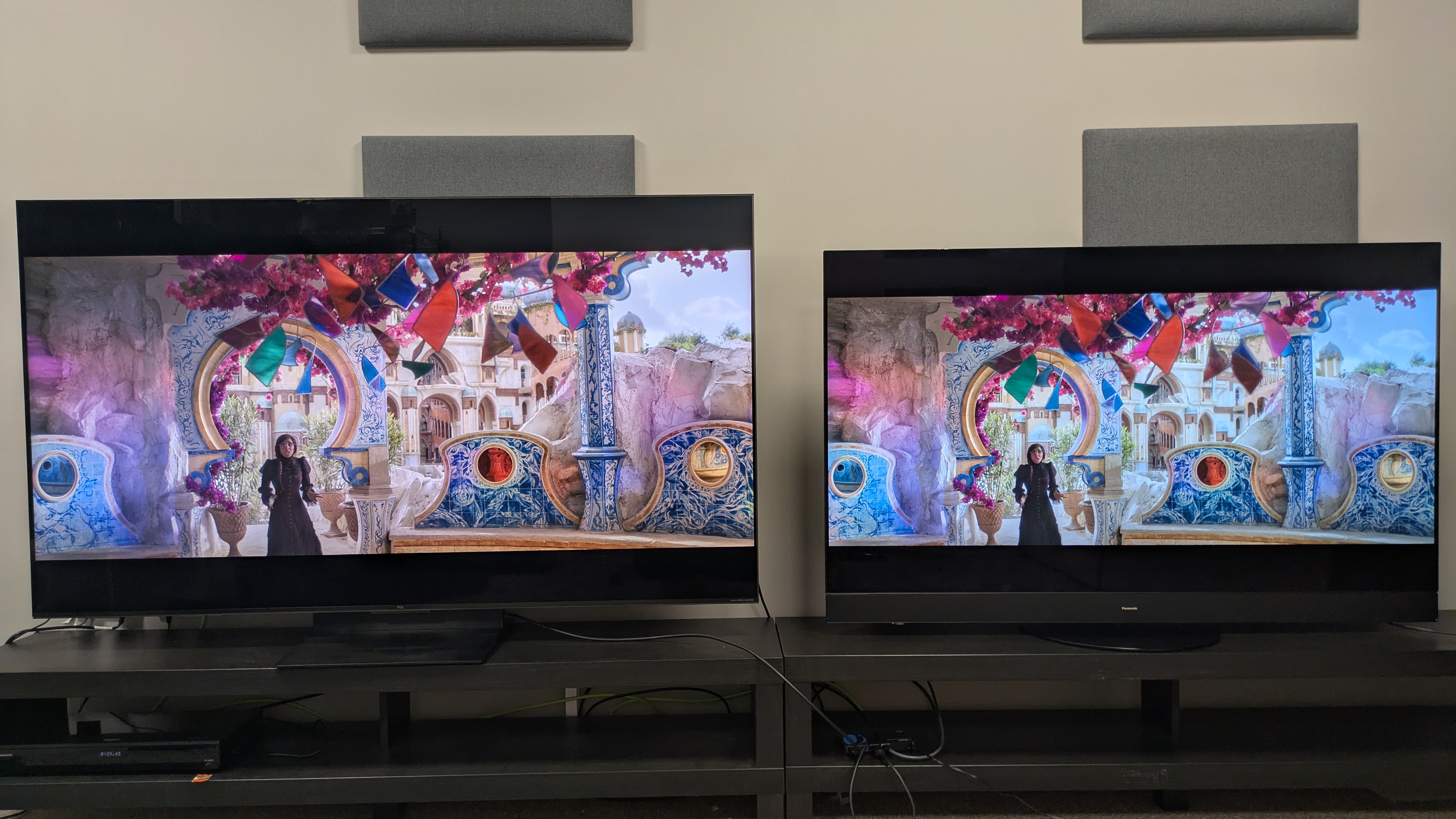 TCL C7K mini-LED left and Panasonic MZ1500 OLED right displaying a Elphaba in a brightly colored room from Wicked on screen