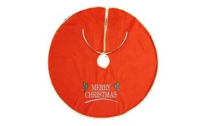 A red Christmas tree skirt with embroidered tree branches. It reads Merry Christmas.