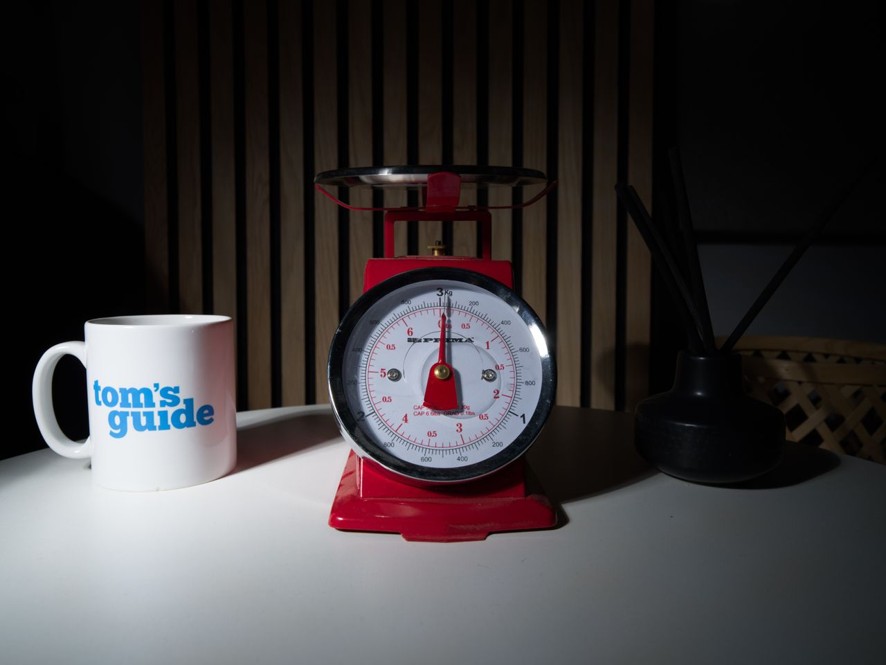 A photo of a set of red scales, with a Tom's Guide mug and a diffuser pot set either side.