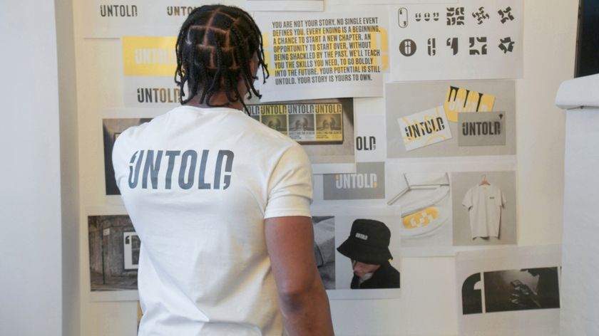 Here Design process of creating Untold identity with young male prisoners - man with untold t-shirt looking at mood board