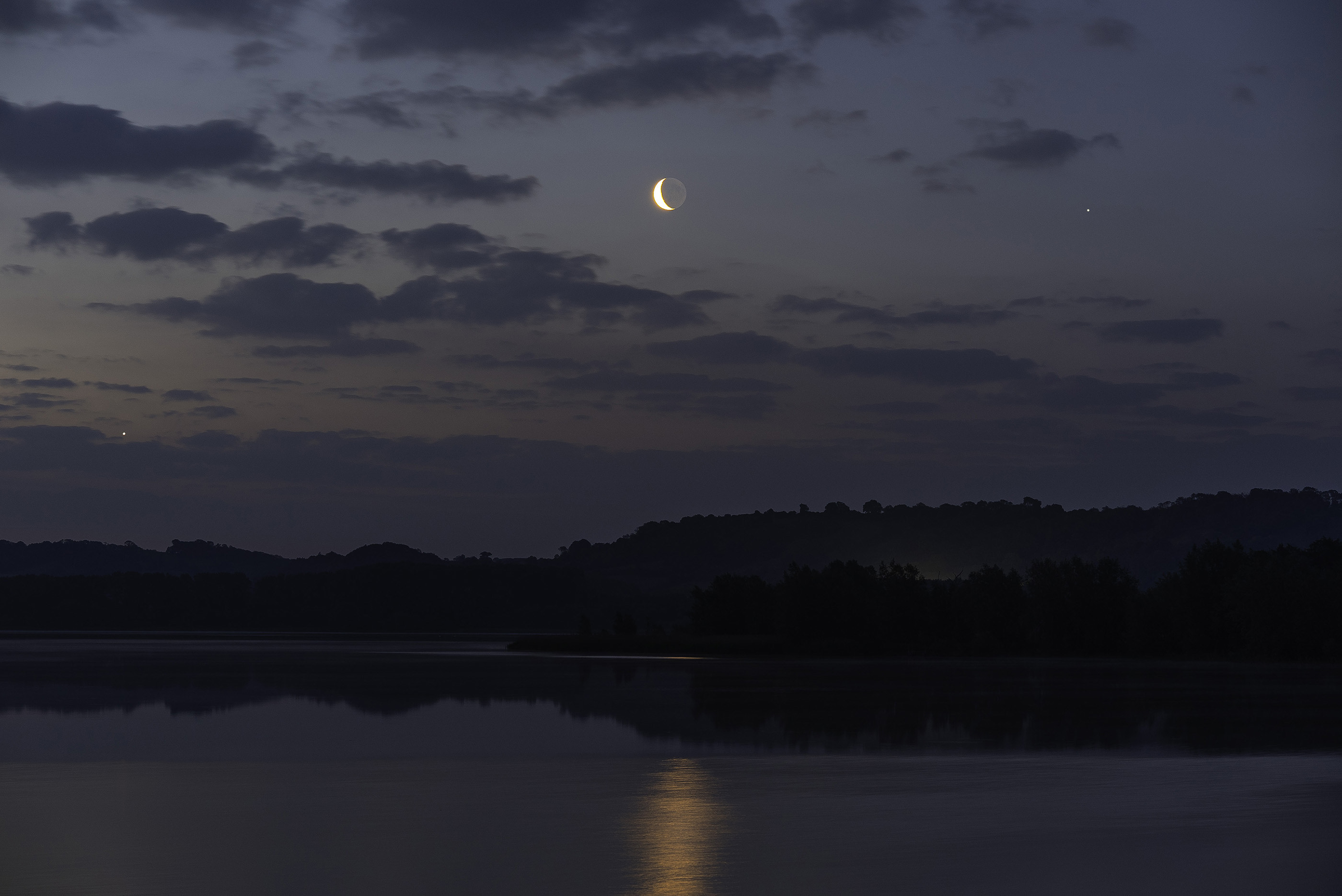 night sky image showing the moon shining in the center with Venus to the left and Saturn to the right.