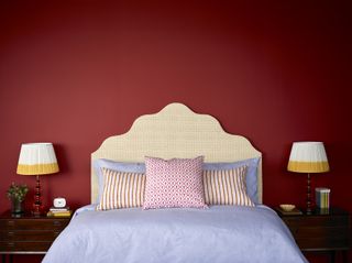 red bedroom with matching bedside lamps, patterned headboard and cushions