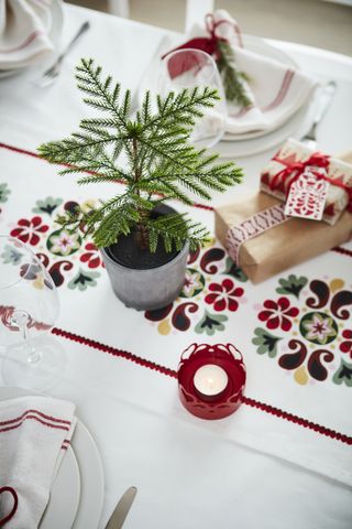 red and white Scandi table with floral runner, small tree, gifts and tea lights