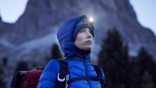 A woman hiking in the mountains wearing a headlamp