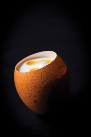 Close up of a tilted open top boiled egg, with a view of the yolk inside, black background