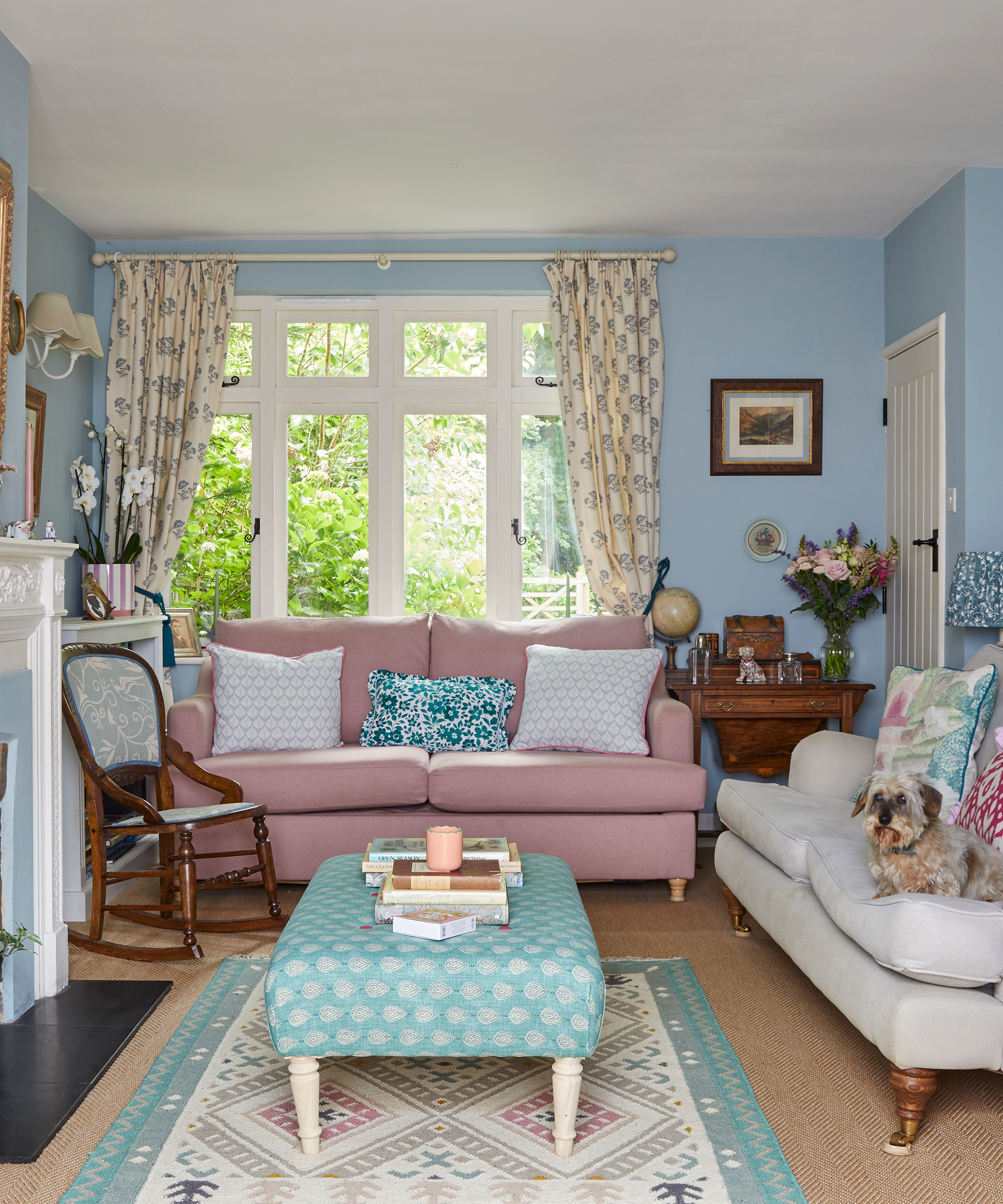 colourful country living room with pale blue walls, pink and beige sofas and mixed patterned cushions and fabrics