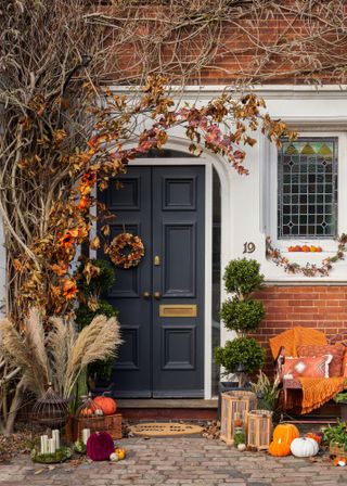 An outdoors with small pumpkins, a lanterns, hay stack, and fall plants