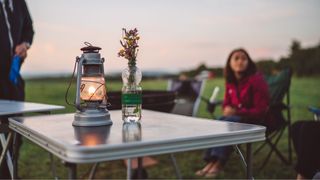 Camping table with flowers in water bottle and lantern