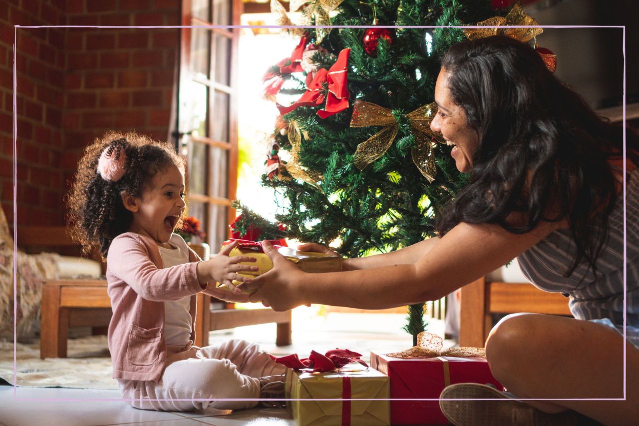 mum giving daughter a Christmas present under the tree