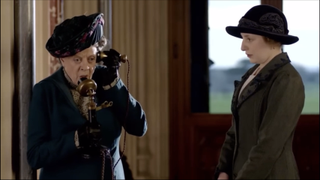 Dame Maggie Smith as the Dowager Countess speaking on a telephone for the first time standing next to Laura Carmichael as Lady Edith.