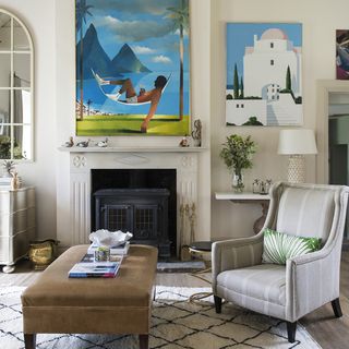 seating area with white wall and pictures and wooden floor with arm chair and fireplace