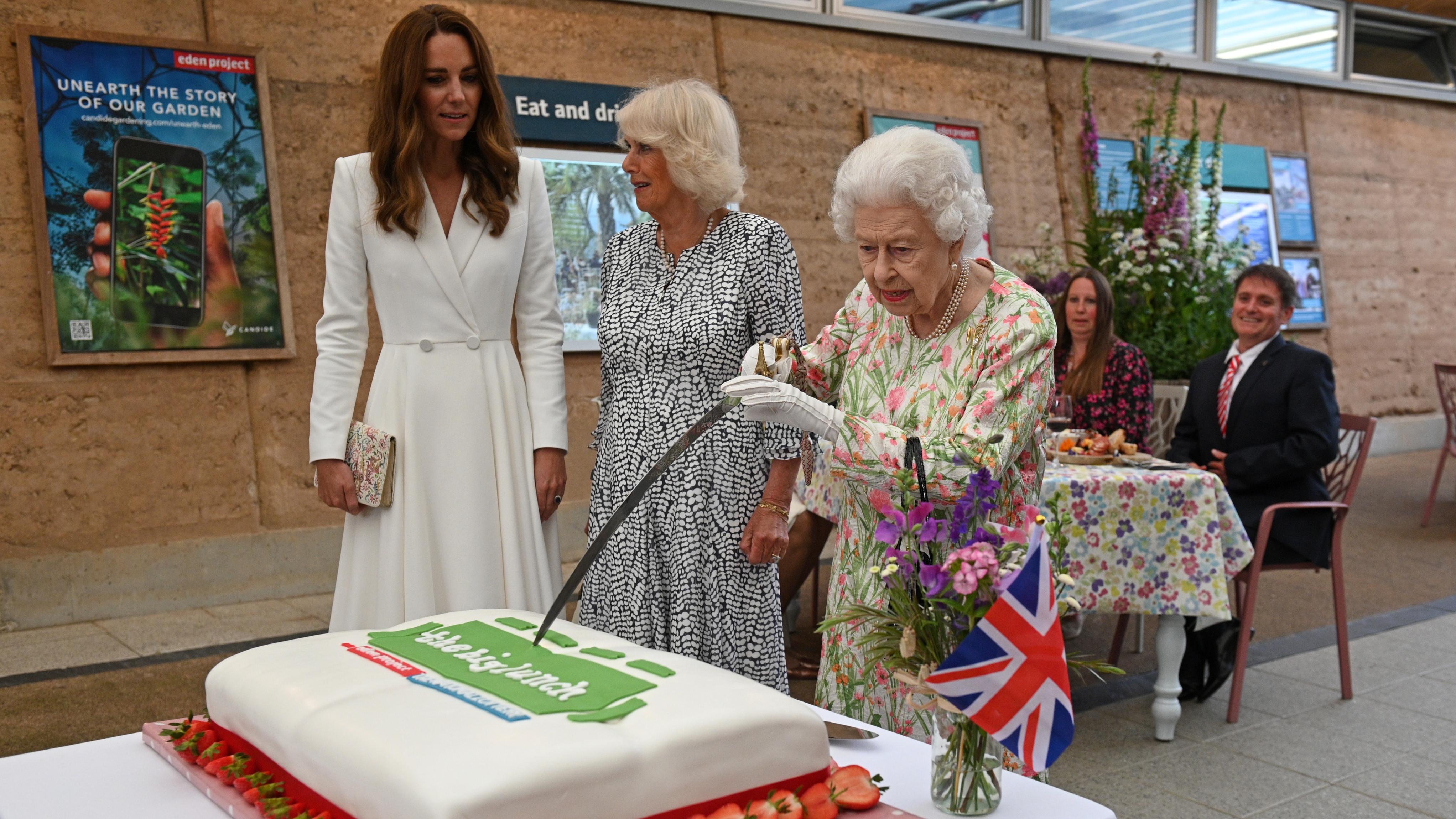Queen Elizabeth attempts to cut a cake with a sword, lent to her by The Lord-Lieutenant of Cornwall, Edward Bolitho, to celebrate of The Big Lunch initiative