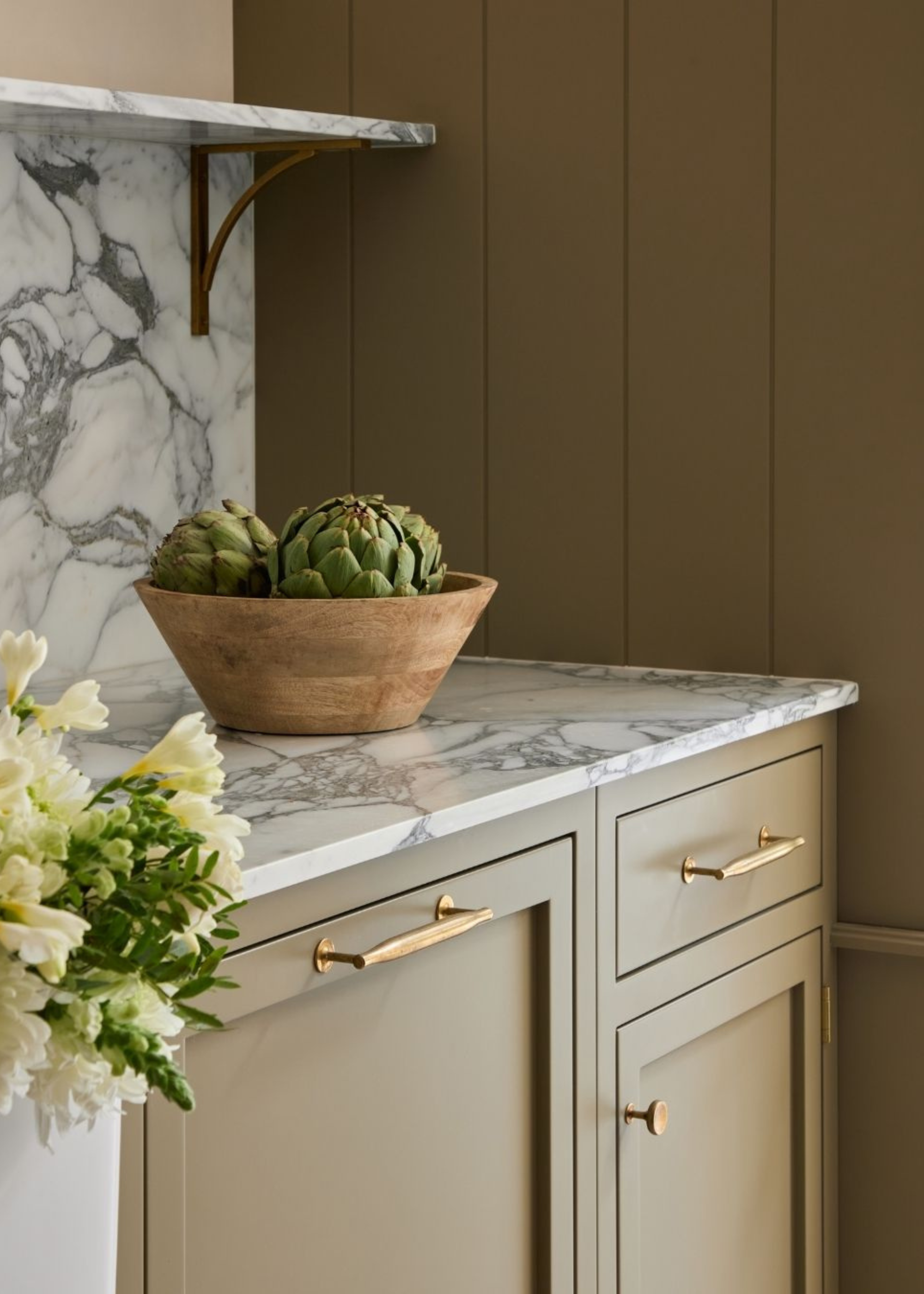 antiqued gold handles on brown kitchen cabinets with marble counters