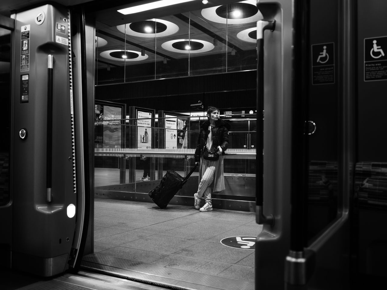 Mono image of a person standing outside a subway carriage, taken on the OM System OM-3 with the OM System M.Zuiko 17mm f/1.8 II