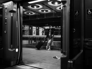 Mono image of a person standing outside a subway carriage, taken on the OM System OM-3 with the OM System M.Zuiko 17mm f/1.8 II