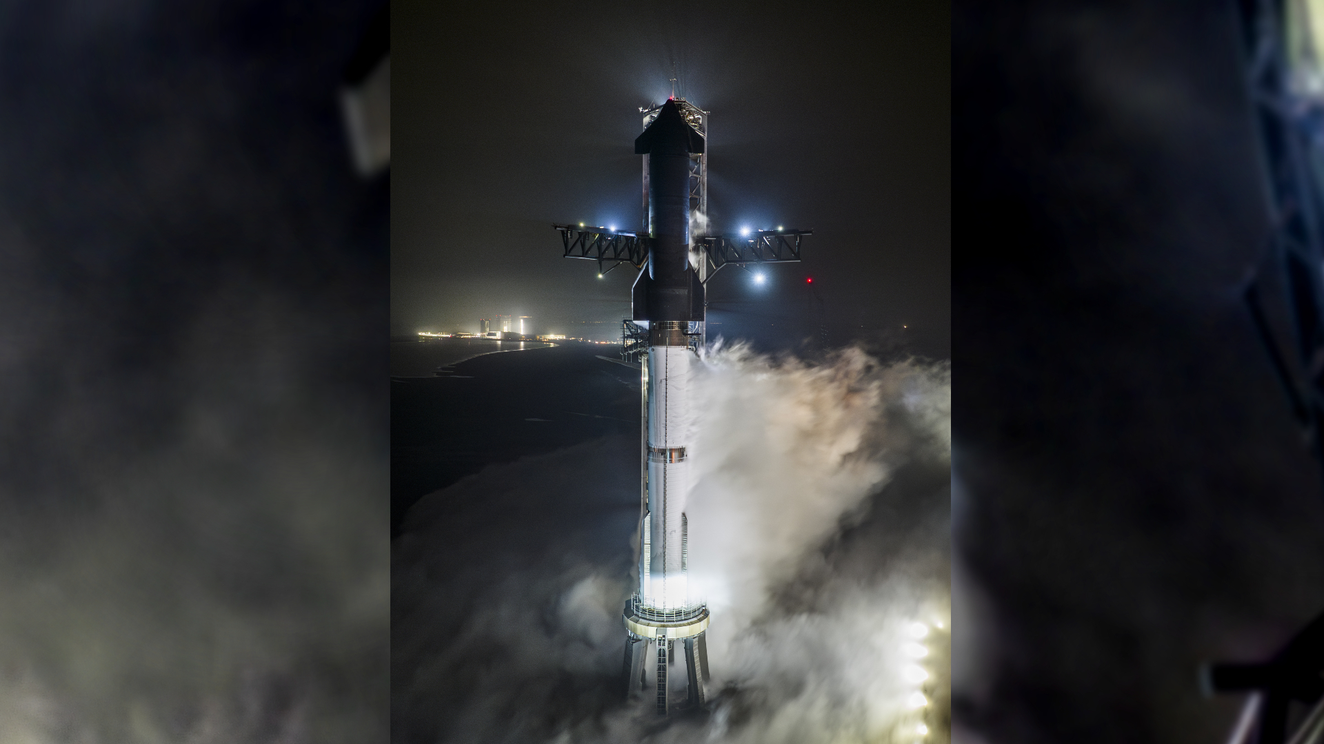 A Starship Flight 3 rocket and Super Heavy booster above the launch pad at night in a fueling test