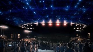 hundreds of people are gathered around a spaceship-looking object with many lights glowing