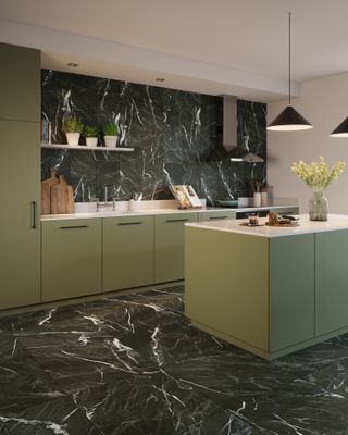 Green kitchen cabinets and black and white marble flooring and splashbacks.