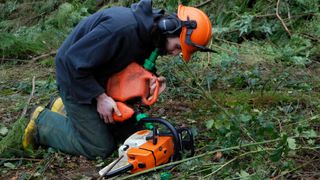 Man filling up chainsaw with oil