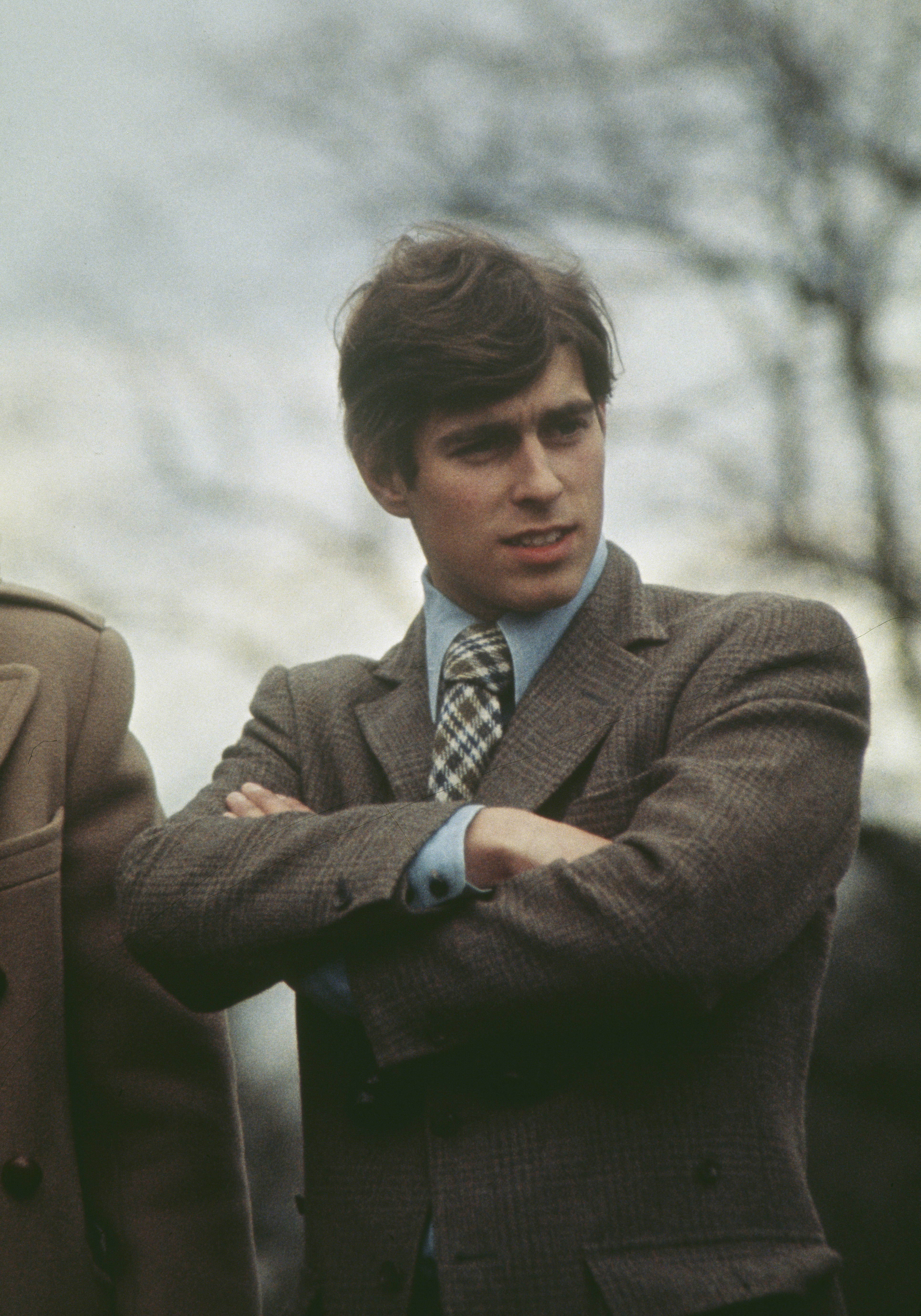 Prince Andrew wearing a brown tweed blazer folding his arms