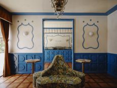interiors of a bakery with blue paneled walls and a floral print multi directional sofa