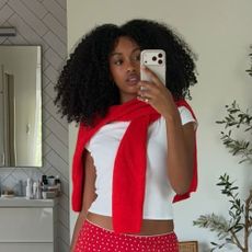 a woman wearing a white tee, red skirt, and flip flops