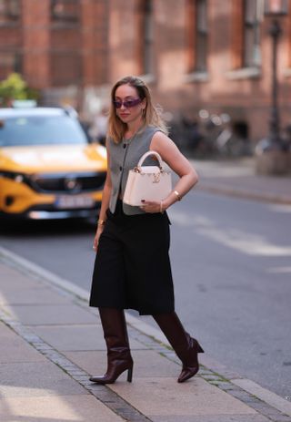 woman wearing bermuda shorts with tailored vest and boots